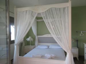 a bedroom with a canopy bed with white curtains at Seaside Boutique Villa in Volos