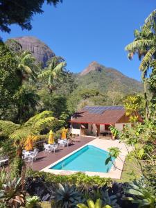 a resort with a pool and mountains in the background at Lumiar Eco Lodge - Chalé Pedra Riscada in Nova Friburgo