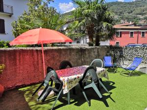 a table and chairs under a red umbrella at Residenza Silvana Apt Cielo and Apt Giardino on the ground floor with parking in Verbania