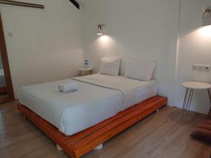 1 cama blanca con marco de madera en una habitación en Waroeng Senaru, en Senaru