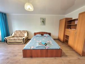 een slaapkamer met een bed en een stoel bij 1 комн. Апартаменты на Абая 122 in Köksetaw