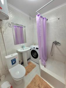 a white bathroom with a toilet and a sink at 1 комн. Апартаменты на Абая 122 in Kokshetau
