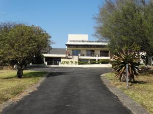 a road in front of a building with trees at Pyramids Motel in Van Reenen