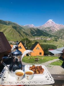 a table with two cups of tea and a plate of food at Guesthouse Elli & Cottages in Stepantsminda