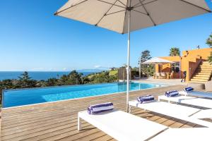 a swimming pool with two lounge chairs and an umbrella at The Villino at Cypress Ridge Estate in Onetangi