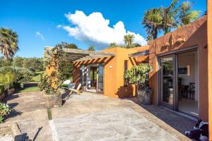 an orange house with a patio and palm trees at The Villino at Cypress Ridge Estate in Onetangi