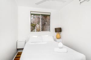 a white bedroom with a bed and a window at Wategos Surf Shack in Byron Bay
