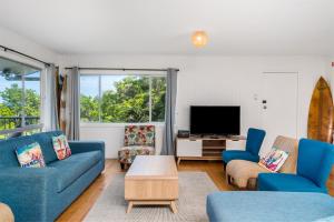 a living room with blue furniture and a flat screen tv at Wategos Surf Shack in Byron Bay