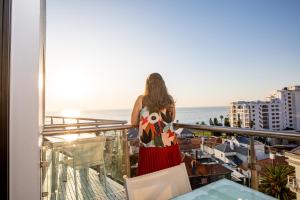 a woman standing on a balcony looking out at the ocean at President Hotel in Cape Town