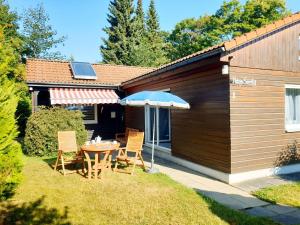 eine Terrasse mit Tisch und Stühlen und einem Sonnenschirm in der Unterkunft Ferienhaus Siesta Hahnenklee mit großem Grundstück in Hahnenklee-Bockswiese