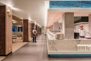 a chef standing in front of a counter in a restaurant at Oceanfront Beach Resort - SHA Extra Plus in Patong Beach