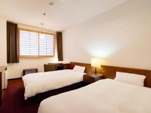 a hotel room with two beds and a window at Hotel Flags Kuju Kusima in Sasebo