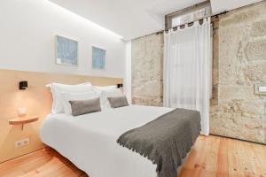 um quarto com uma grande cama branca e uma parede de tijolos em OX Apartments B Places em Porto