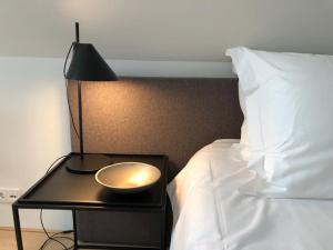 Una cama con lámpara y una mesa con un tazón. en Het Wagenhuis, en Loon op Zand