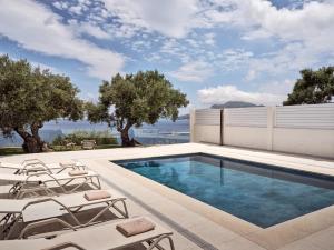 a swimming pool with lounge chairs next to a house at Stelle Mare Villa in Akrotiri