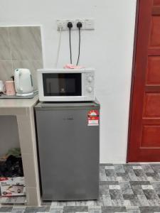 a microwave sitting on top of a refrigerator at Homestay Idaman B B with 2 room aircond 2 Quen Bed and Not Sharing Room -Privacy in Kuala Terengganu