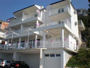 um edifício de apartamentos branco com ursos de peluche cor-de-rosa nas varandas em Apartments with a parking space Pisak, Omis - 4281 em Mimice