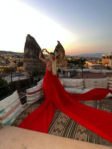 Una mujer con un vestido rojo parada en un techo en Adora Cave Suites - en Göreme