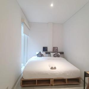 um quarto com uma cama com lençóis brancos e uma janela em Tengah Tengah em Jakarta