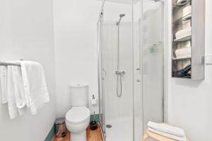 uma casa de banho com um WC e uma cabina de duche em vidro. em OX Apartments B Places no Porto