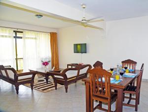 a living room with a dining room table and chairs at Galu Gardens Apartments Diani Beach in Diani Beach
