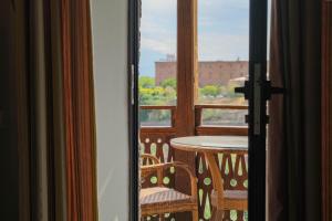 a room with a balcony with a table and a window at Apricot Hotel Yerevan in Yerevan