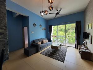 a living room with blue walls and a couch at Cameron Forest Home - Golden Hills in Cameron Highlands