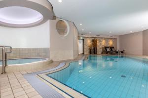 a swimming pool in a hotel room with a tub at Hotel Heidegrund in Petersfeld