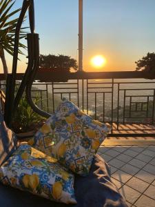 un divano con due cuscini su un balcone con vista sul tramonto di Or Son Sano a Lettere