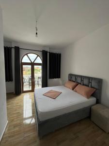 a bedroom with a large bed and a large window at Vila Sidi in Ksamil
