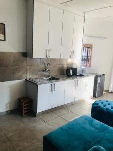 a kitchen with white cabinets and a sink at Shamrock Place in Roodepoort
