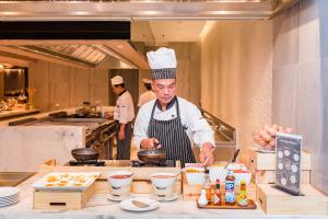 a chef standing in a kitchen preparing food at Oceanfront Beach Resort - SHA Extra Plus in Patong Beach