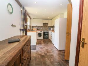 a kitchen with a white refrigerator and a tile floor at Barn Cottage in Penzance