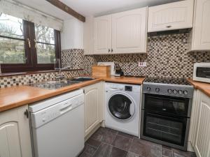 a kitchen with white cabinets and a washer and dryer at Barn Cottage in Penzance +23 photos