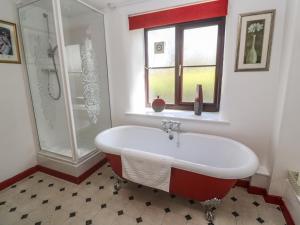 ein Bad mit einer Badewanne, einer Dusche und einem Fenster in der Unterkunft Barn Cottage in Penzance