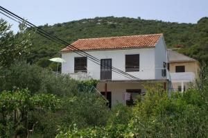 ein weißes Haus mit einem Balkon vor einem Hügel in der Unterkunft Apartments by the sea Vrgada, Biograd - 4206 in Biograd na Moru