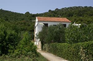 a small white house on a hill next to a road at Apartments by the sea Vrgada, Biograd - 4206 in Biograd na Moru