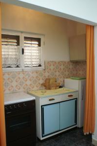 a small kitchen with a stove and a refrigerator at Apartments by the sea Vrgada, Biograd - 4206 in Biograd na Moru