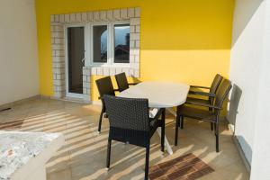 une table et des chaises dans une pièce dotée d'un mur jaune dans l'établissement Apartments by the sea Grebastica, Sibenik - 4254, à Šibenik