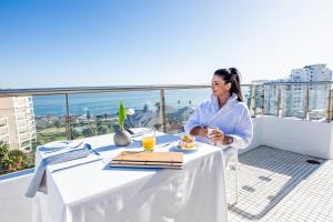 een vrouw aan een tafel op een balkon bij President Hotel in Kaapstad