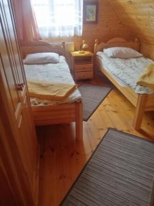 two beds in a room with wooden floors at Dom Gościnny Matysowka in Jarosławiec