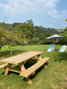 a wooden picnic table and two chairs and an umbrella at Casa de campo en pleno centro de Asturias in Sesiello