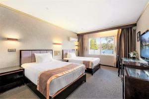 a hotel room with two beds and a television at Eltham Gateway Hotel & Conference Centre in Eltham
