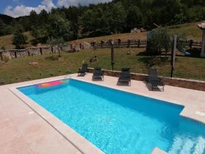 a swimming pool with four chairs at Holiday house Dol in Cerovlje
