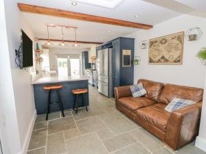 a living room with a leather couch and a kitchen at Y Bwythyn Bach in Burry Port