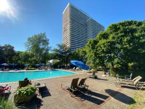 a swimming pool with chairs and a tall building at Timmendomizil - schöne Ferienwohnung in bester Lage - Sonnenseite in Timmendorfer Strand