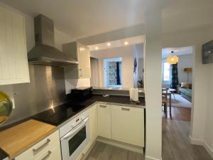 a kitchen with white cabinets and a living room at L'Abri-gîte - Appartement moderne idéalement situé en centre ville in Dieppe