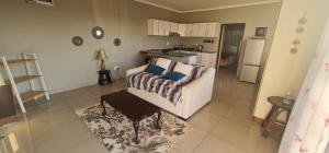 a living room with a couch and a kitchen at Cosy Cottage in Port Shepstone