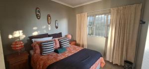 a bedroom with a bed with pillows and a window at Cosy Cottage in Port Shepstone