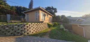 a house with a retaining wall next to a fence at Cosy Cottage in Port Shepstone